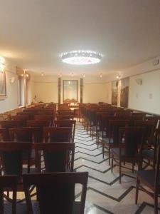 una stanza vuota con sedie e tavoli e un lampadario a braccio di Villa Sacro Cuore a San Giovanni Rotondo