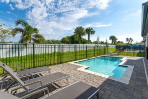 a swimming pool with chairs and a fence at Wonderful 8Bd7BA Melbourne Beach w Pool Dock & Beach in Melbourne Beach