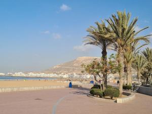 une plage avec des palmiers et une montagne en arrière-plan dans l'établissement marinamarina, à Agadir