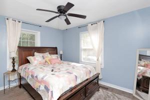 a bedroom with a bed with a ceiling fan at Adorable Blue Little House in Charleston
