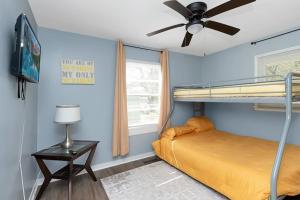 a bedroom with a bunk bed and a ceiling fan at Adorable Blue Little House in Charleston