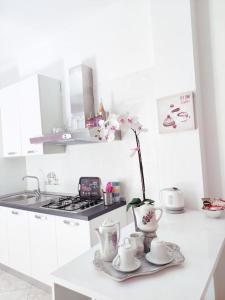 una cucina bianca con tavolo con tazze e vaso di Apulia mon amour (Apulian Charming Apartement) a Mola di Bari