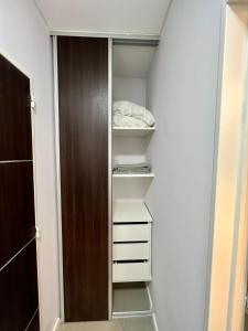 um armário com prateleiras brancas e uma porta de madeira em Loft Dorrego Rio em Rosário