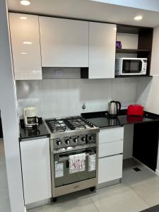 uma cozinha com armários brancos e um forno com placa de fogão em Loft Dorrego Rio em Rosário