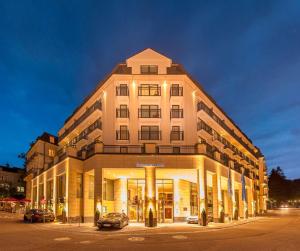 un grand bâtiment avec des voitures garées devant lui dans l'établissement Maison Messmer - ein Mitglied der Hommage Luxury Hotels Collection, à Baden-Baden
