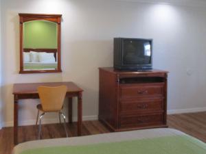 a room with a television on a dresser with a mirror at Motel 6-Fresno, CA in Fresno
