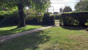 un camino en un patio con dos árboles y una valla en Casa de Huéspedes Muñiz sobre parque de 1000m2, 1 dormitorio, 20m2 cubiertos, baño con ducha, pileta cilíndrica de 3x076 en 