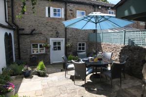 un patio con una mesa con una sombrilla azul en Number 10, Whalley, en Whalley