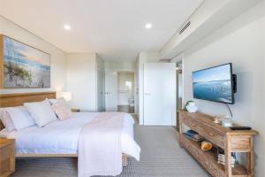a bedroom with a bed and a flat screen tv at Footprints 1 in Fingal Bay