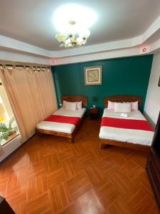 Habitación con 2 camas, paredes verdes y suelo de madera. en Hotel Wilson Upala, en Upala