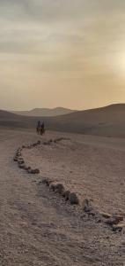 Dos personas están montando caballos en el desierto en Terre D'agafay, en Aït Mazou