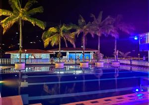 a pool with purple chairs and palm trees at night at VillaLoren in San Antonio del Tequendama