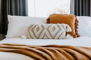 uma cama branca com almofadas castanhas e um cobertor castanho em Federal Hotel Mudgee em Mudgee