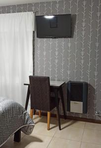 um quarto com uma secretária, uma televisão e uma cama em Hotel Miceli em Bragado