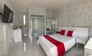 1 dormitorio con 1 cama blanca grande con almohadas rojas en Sena Gladyz Suites, en Panabo