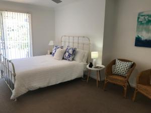 a bedroom with a bed and a chair and a window at Beachfront Retreat - Ducted Air - Free Wifi in Coffs Harbour