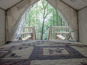 a tent with two chairs and a quilt on a bed at Tentrr Signature Site - Happy Hollow Hideaway Glade site in Pigeon Forge