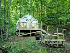 a large tree house in the woods with a bench at Tentrr Signature Site - Happy Hollow Hideaway Creekside in Pigeon Forge