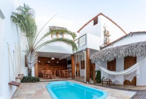 a villa with a swimming pool in front of a house at Villa Chic Pousada in Jericoacoara