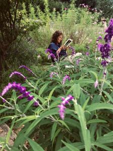 una mujer leyendo un libro en un jardín con flores púrpuras en Posada de la Montaña en La Cumbre