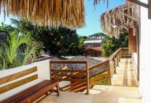 balcón con bancos y sombrilla de palmera en Villa Chic Hostel Pousada, en Jericoacoara