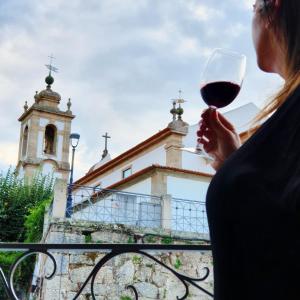 une femme tenant un verre de vin devant une église dans l'établissement O 21 da Vila, à Seia