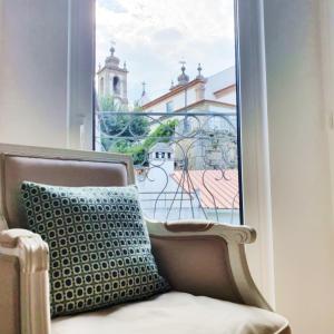 a chair with a pillow sitting in front of a window at O 21 da Vila in Seia