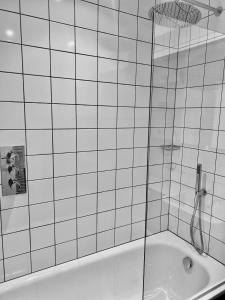 La salle de bains est pourvue de carrelage blanc, d'une douche et d'une baignoire. dans l'établissement Stylish Birmingham City Centre Apartment, à Birmingham
