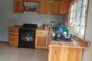 una cocina con armarios de madera y estufa negra en Quiet Cabin in San Gabriel Mixtepec, 
