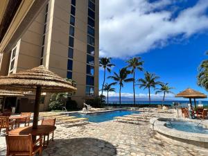 a resort with a swimming pool with chairs and umbrellas at Maui Westside Presents: Mahana 1003 in Lahaina