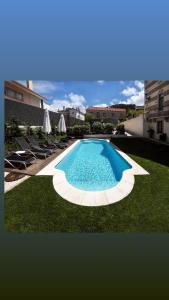 einen Pool im Garten mit Stühlen und Sonnenschirmen in der Unterkunft Chalet Vitorino in Sintra