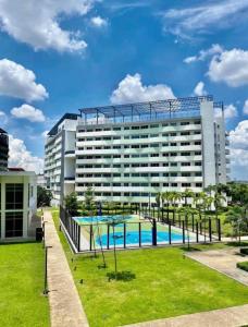 a large building with a swimming pool in front of it at The Residences at Commonwealth by Century in Manila