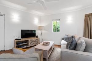 a living room with a couch and a tv at 4 Munna Cove in Noosaville