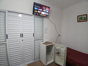 uma televisão numa parede por cima de um pequeno frigorífico em Suíte Independente - Praia Indaiá e Riviera - MarDoceLar Bertioga em Bertioga