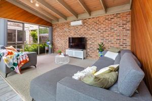 a living room with a couch and a brick wall at Blairgowrie Beach Bungalow in Blairgowrie