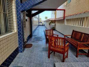 two wooden benches sitting on a porch next to a building at Recanto 101 in Praia Grande
