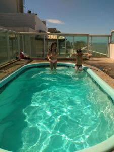 two women are standing in a swimming pool at FLAT frente Mar Green Diamond in Vila Velha