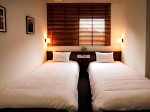 two twin beds in a room with a window at Hotel Pacific Kanazawa in Kanazawa