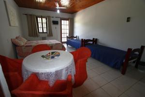 a room with two beds and a table and chairs at Pousada Calvanos Chalés in Rio das Ostras