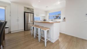 a kitchen with white cabinets and a counter with stools at South Coast Retreat in Inverloch +6 photos