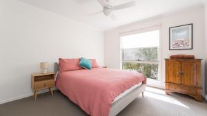 a white bedroom with a bed and a window at South Coast Retreat in Inverloch
