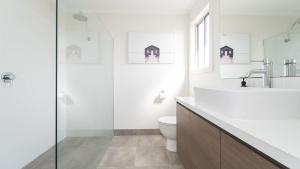 a white bathroom with a toilet and a sink at South Coast Retreat in Inverloch