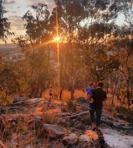 a man and a child standing on a hill with the sunset at A Stanthorpe Getaway in Ballandean