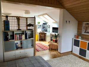a living room with a book shelf and a kitchen at Charmante Ferienwohnung mit Balkon im 5-Seen-Land in Hechendorf am Pilsensee