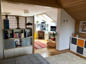 uma sala de estar com uma estante de livros e uma cozinha em Charmante Ferienwohnung mit Balkon im 5-Seen-Land em Hechendorf am Pilsensee