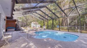 a pool in a glass house with a table and chairs at Blissful Beach Retreat with Screened-in Pool in Ocean Springs