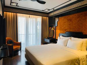 a bedroom with a large bed and a chair at Hotel du Monde Classic in Hanoi