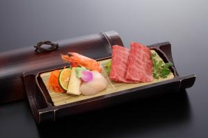 神戶的住宿－寓格斯三思華宇溫泉月光園酒店，盘子上放有肉和蔬菜的寿司