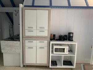 a kitchen with a white cabinet and a microwave at Paradise chez Nono in Baie-Mahault