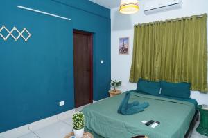a bedroom with blue walls and a bed with a green curtain at Atmos Inn in Kozhikode